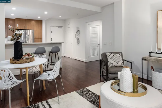 a kitchen with stainless steel appliances kitchen island granite countertop a dining table chairs and a refrigerator