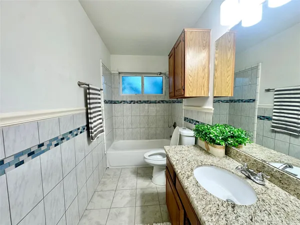 a bathroom with a granite countertop tub a sink and a large mirror