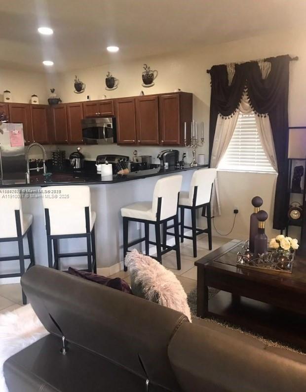 11343 Southwest 239 Street, Unit 11343 Homestead, FL 33032 - Photo 6 of 12 a living room with stainless steel appliances kitchen island a table and chairs in it