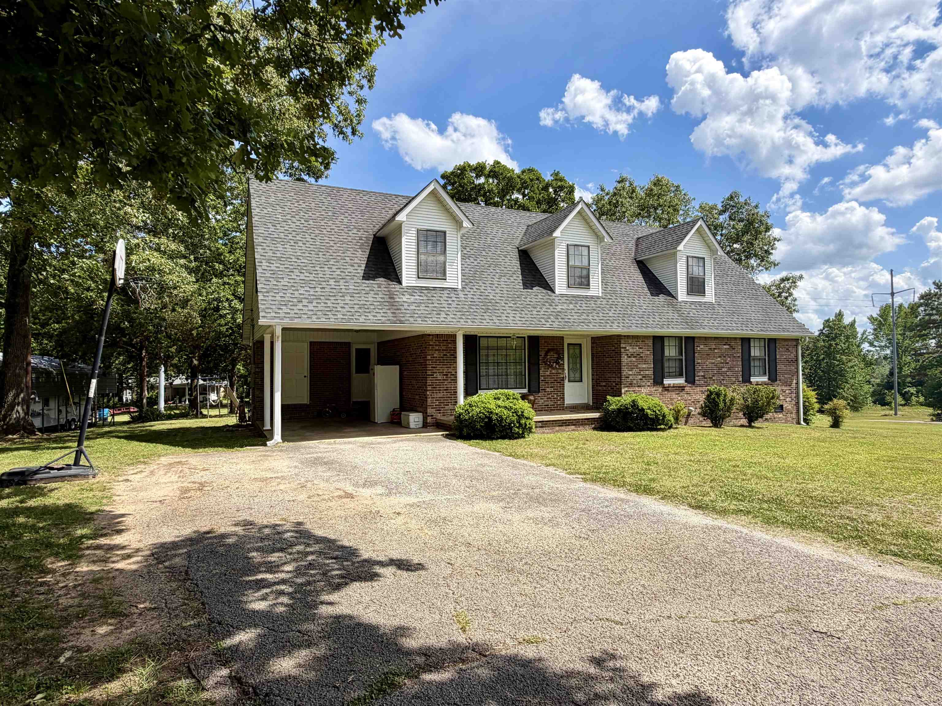 142 Treece Street Selmer, TN 38375 - Photo 33 of 36 Brick-front home featuring a gray shingle roof and white dormer windows