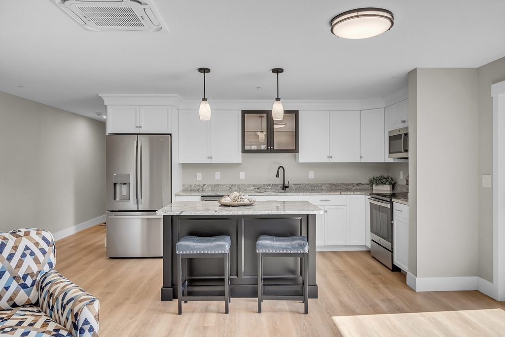 50 Main Street, Unit 101 Pepperell, MA 01463 - Photo 4 of 20 a kitchen with stainless steel appliances granite countertop a sink stove and refrigerator
