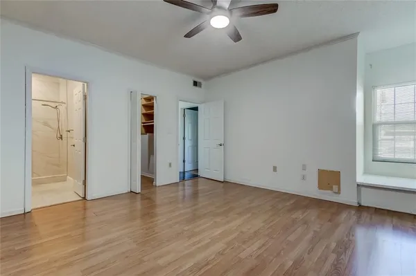 an empty room with wooden floor chandelier fan and windows