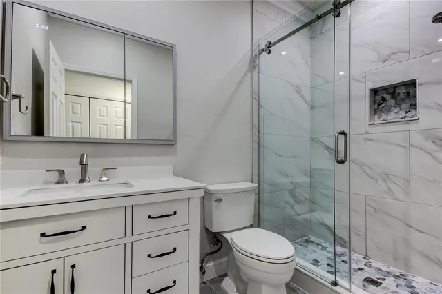a bathroom with a granite countertop sink toilet a mirror and shower
