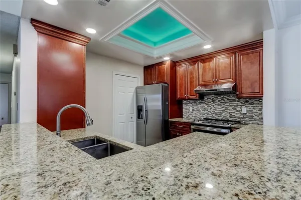 a kitchen with stainless steel appliances kitchen island granite countertop a refrigerator and a sink