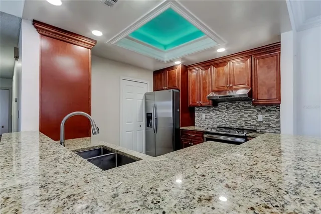 a kitchen with stainless steel appliances kitchen island granite countertop a refrigerator and a sink