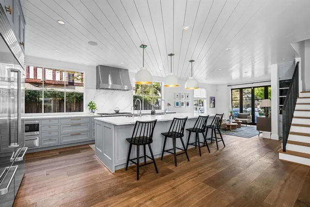 a kitchen with stainless steel appliances granite countertop wooden floor a dining table and chairs