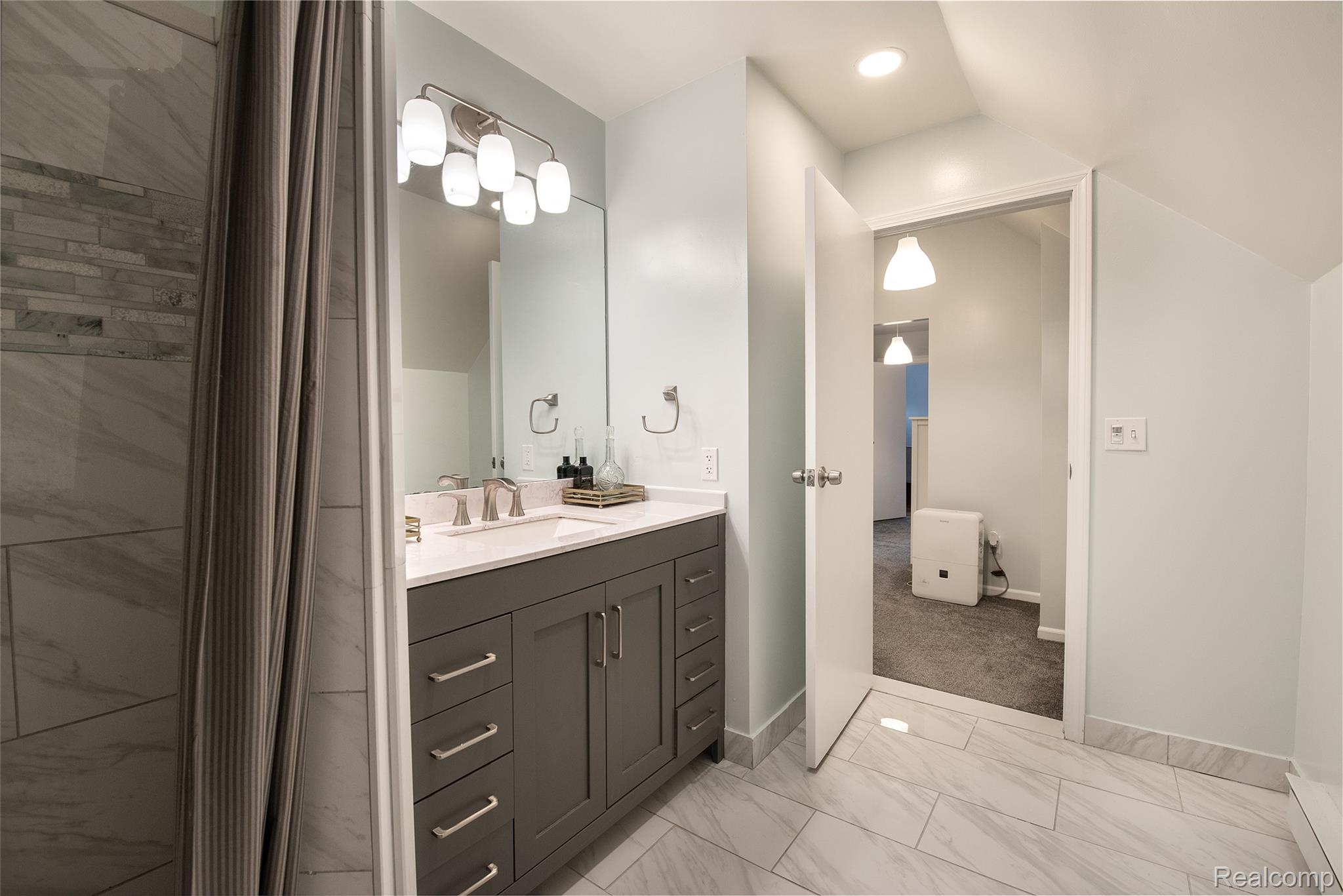 22 Cloverport Avenue Rochester, MI 48307 - Photo 19 of 48 Spa-inspired primary bathroom featuring a dual-sink vanity with dark cabinetry, brushed nickel hardware, and a quartz countertop