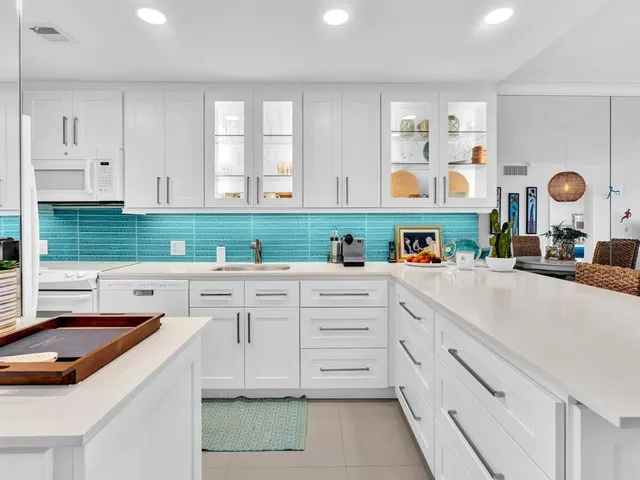 a kitchen that has white cabinets a stove and a sink