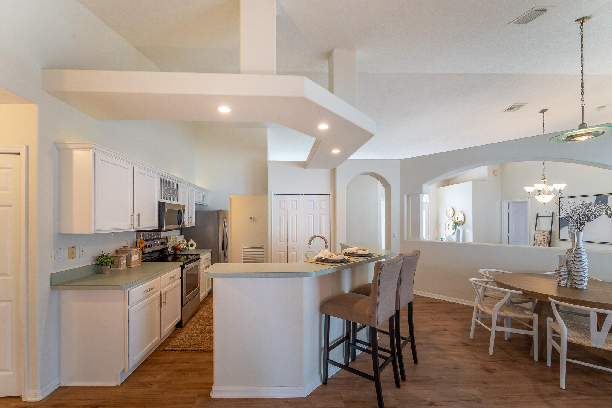 513 Southeast Cliff Road Port St. Lucie, FL 34984 - Photo 15 of 31 a kitchen with kitchen island a dining table chairs and white cabinets