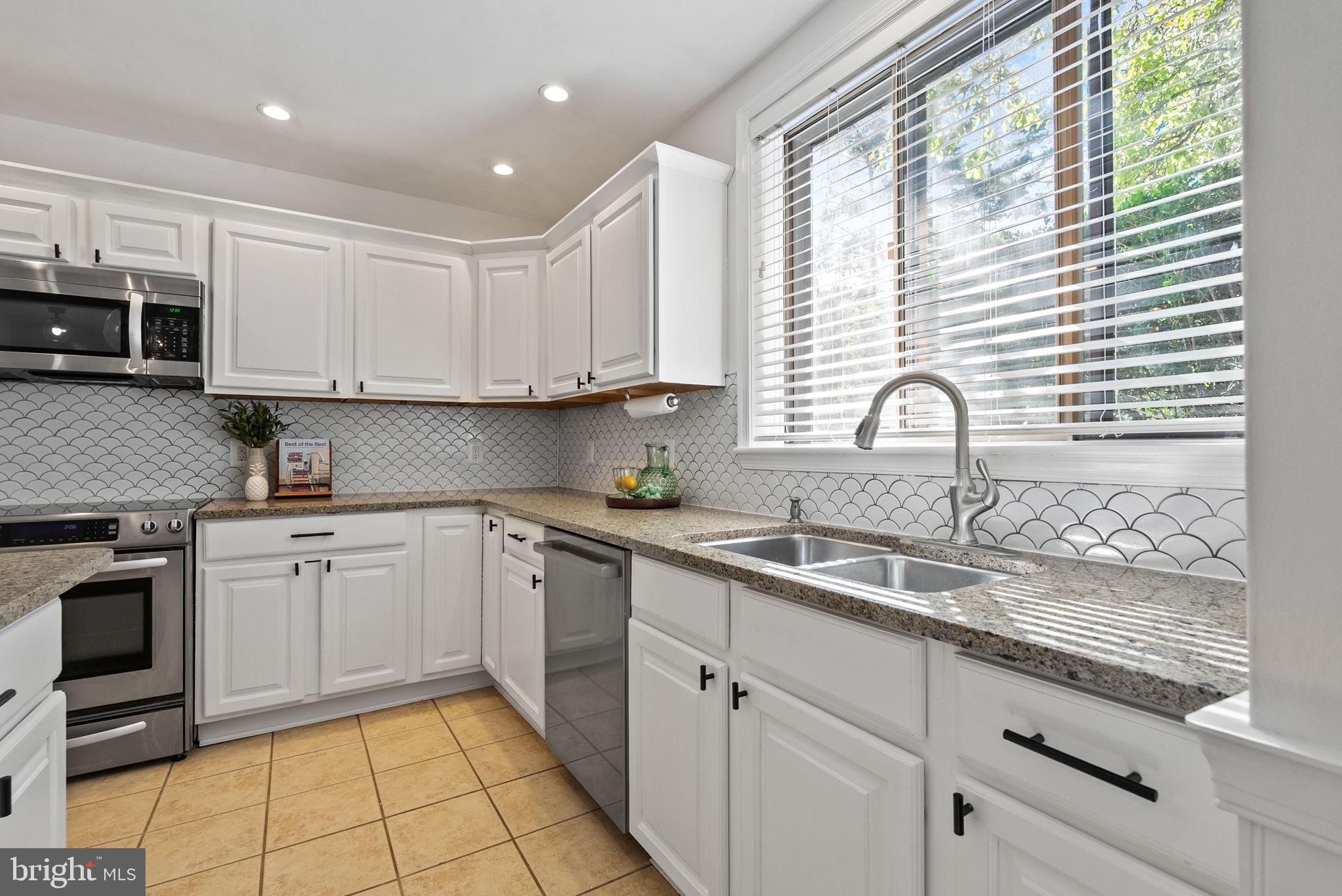 11026 Saffold Way Reston, VA 20190 - Photo 21 of 30 a kitchen with kitchen island granite countertop a sink stainless steel appliances and white cabinets