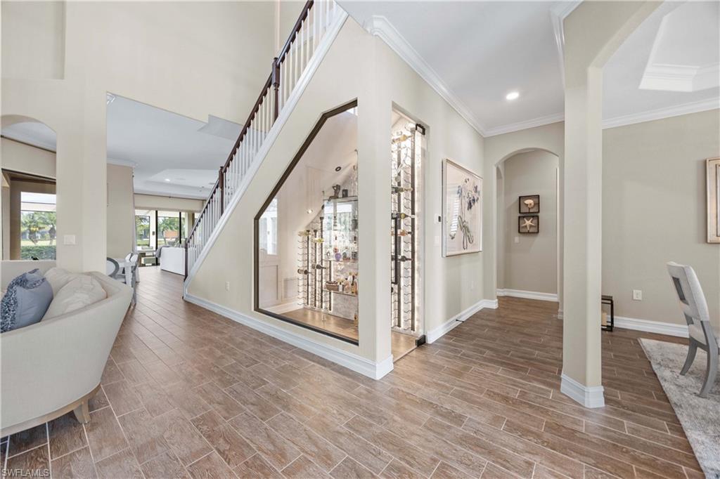 9852 Corso Bello Drive Naples, FL 34113 - Photo 11 of 50 Corridor with arched walkways, crown molding, wood tiled floors, recessed lighting, and stairway