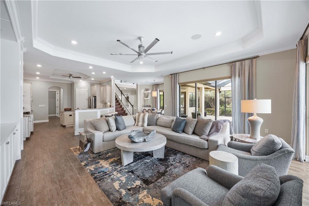 9852 Corso Bello Drive Naples, FL 34113 - Photo 17 of 50 Living area with a ceiling fan, ornamental molding, wood finished floors, arched walkways, and a raised ceiling