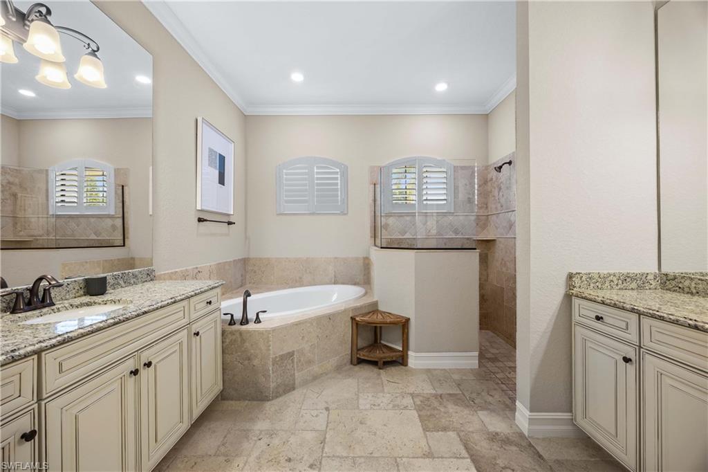 9852 Corso Bello Drive Naples, FL 34113 - Photo 24 of 50 Full bathroom with stone tile flooring, a bath, two vanities, walk in shower, and crown molding