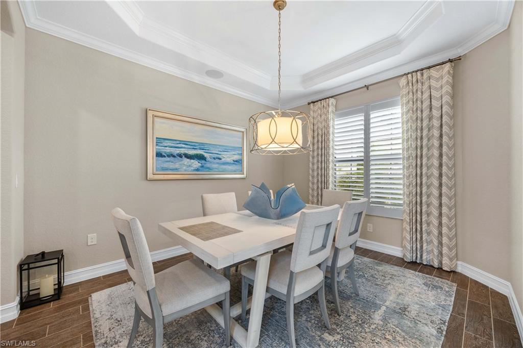 9852 Corso Bello Drive Naples, FL 34113 - Photo 28 of 50 Dining area with wood finish floors, crown molding, and a tray ceiling