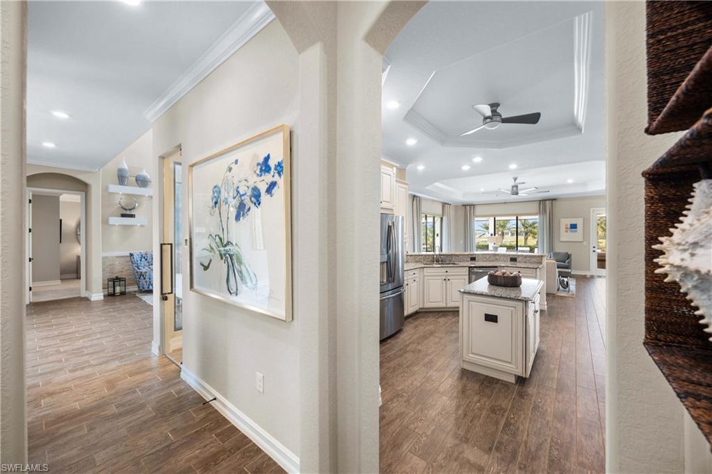 9852 Corso Bello Drive Naples, FL 34113 - Photo 39 of 50 Hallway featuring arched walkways, ornamental molding, dark wood-style flooring, recessed lighting, and a raised ceiling