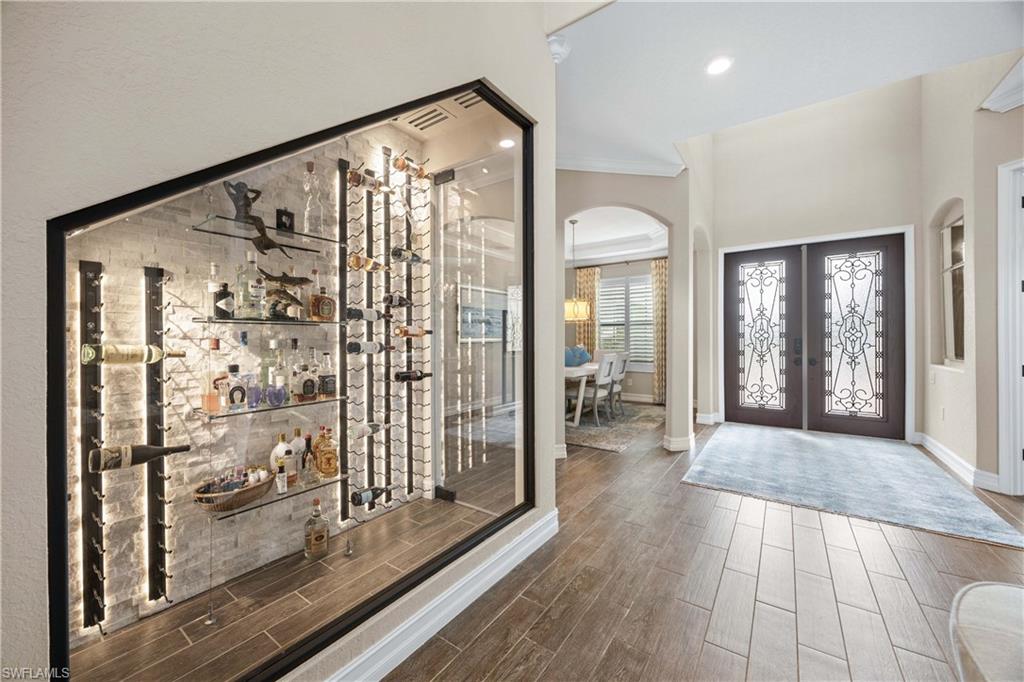 9852 Corso Bello Drive Naples, FL 34113 - Photo 9 of 50 Wine room featuring arched walkways, wood finish floors, crown molding, french doors, and recessed lighting