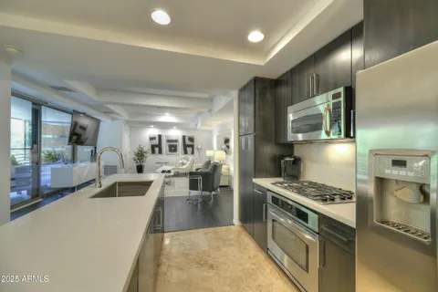 a large kitchen with stainless steel appliances a stove a refrigerator a sink dishwasher with a dining table and chairs