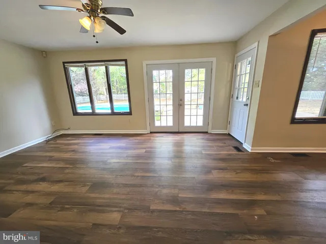 a view of an empty room with window and wooden floor