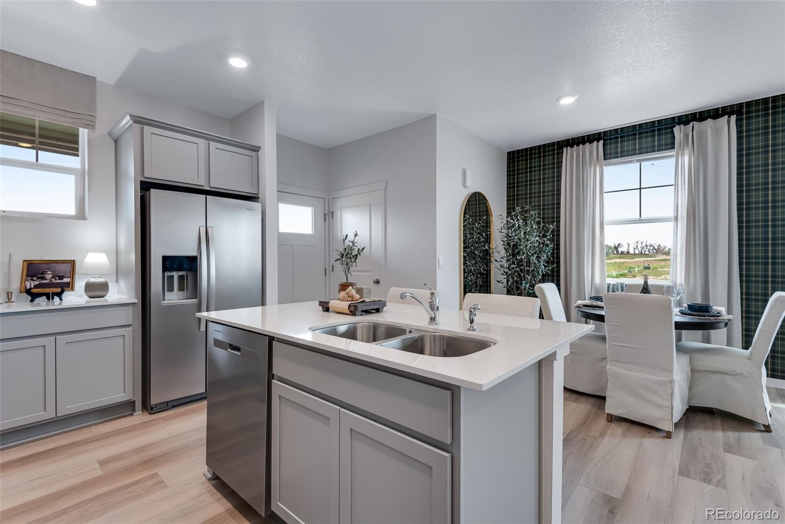 612 South Cabernet Avenue Fort Lupton, CO 80621 - Photo 20 of 49 a room with stainless steel appliances kitchen island granite countertop a refrigerator a sink dishwasher stove and couches with wooden floor