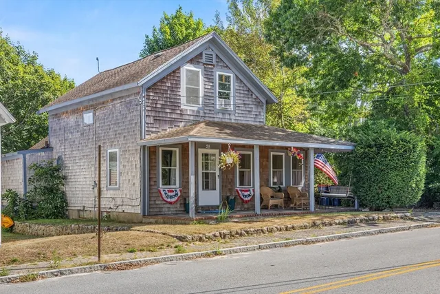 a view of a house with a yard plants and large tree
