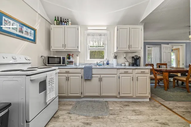 a kitchen with white cabinets appliances and a window