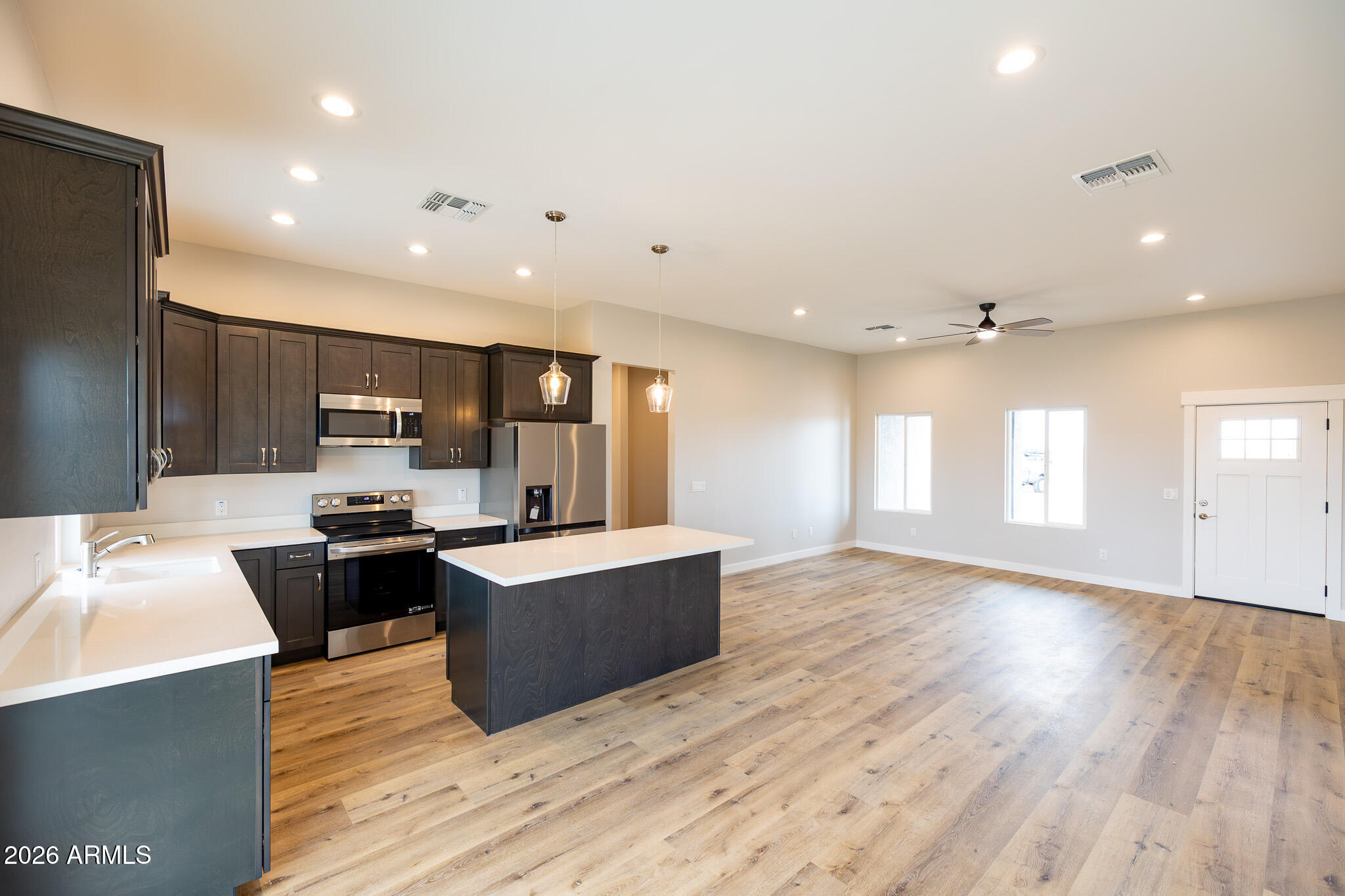 11459 East Adamsville Road Florence, AZ 85132 - Photo 13 of 63 a living room with stainless steel appliances kitchen island granite countertop a sink dishwasher a refrigerator and a oven with wooden floor