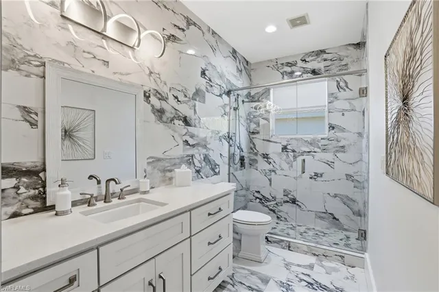 a bathroom with a granite countertop sink toilet and shower