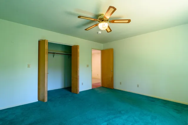 an empty room with closet and a ceiling fan