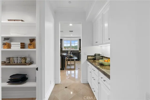 a spacious bedroom with a bed a chandelier with the dresser and mirror