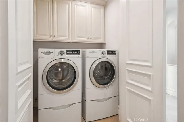 a view of a white house with a yard potted plants and large tree