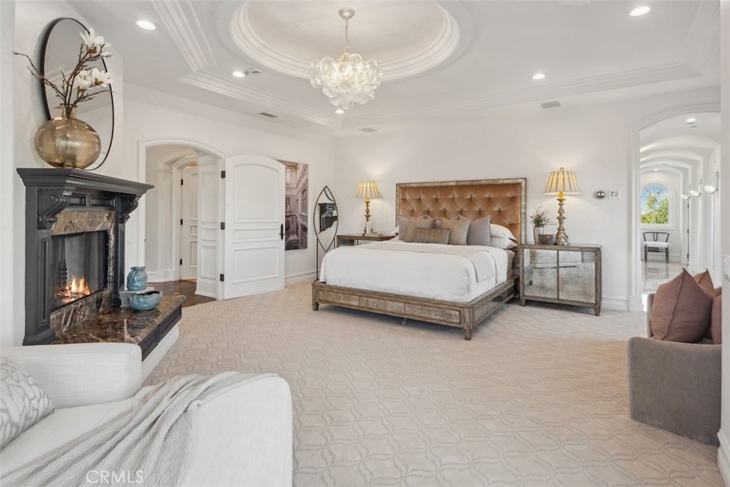 28 Shoreridge Newport Coast, CA 92657 - Photo 39 of 75 a spacious bedroom with a bed a chandelier with the dresser and mirror