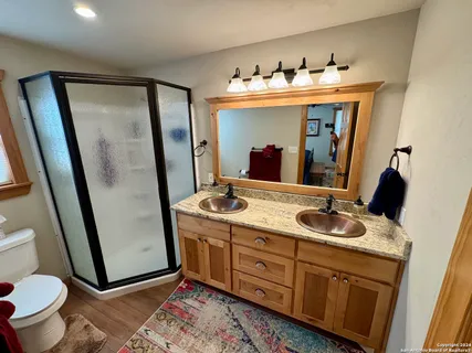 a bathroom with a granite countertop sink and mirror with toilet