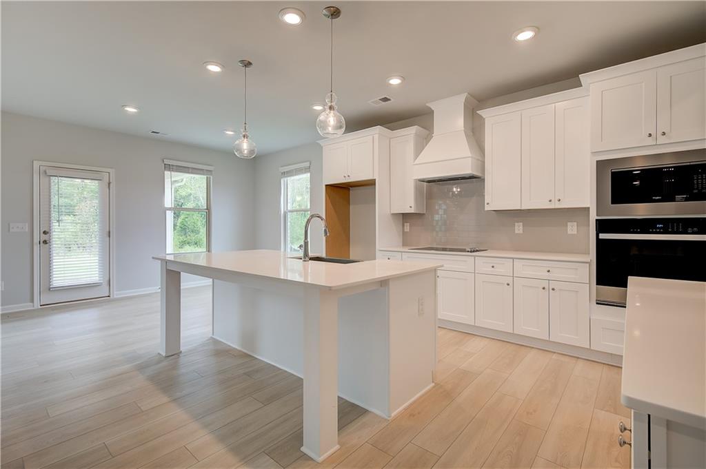 343 Linford Drive Locust Grove, GA 30248 - Photo 7 of 36 a kitchen with stainless steel appliances granite countertop a stove a sink a refrigerator and white cabinets with wooden floor
