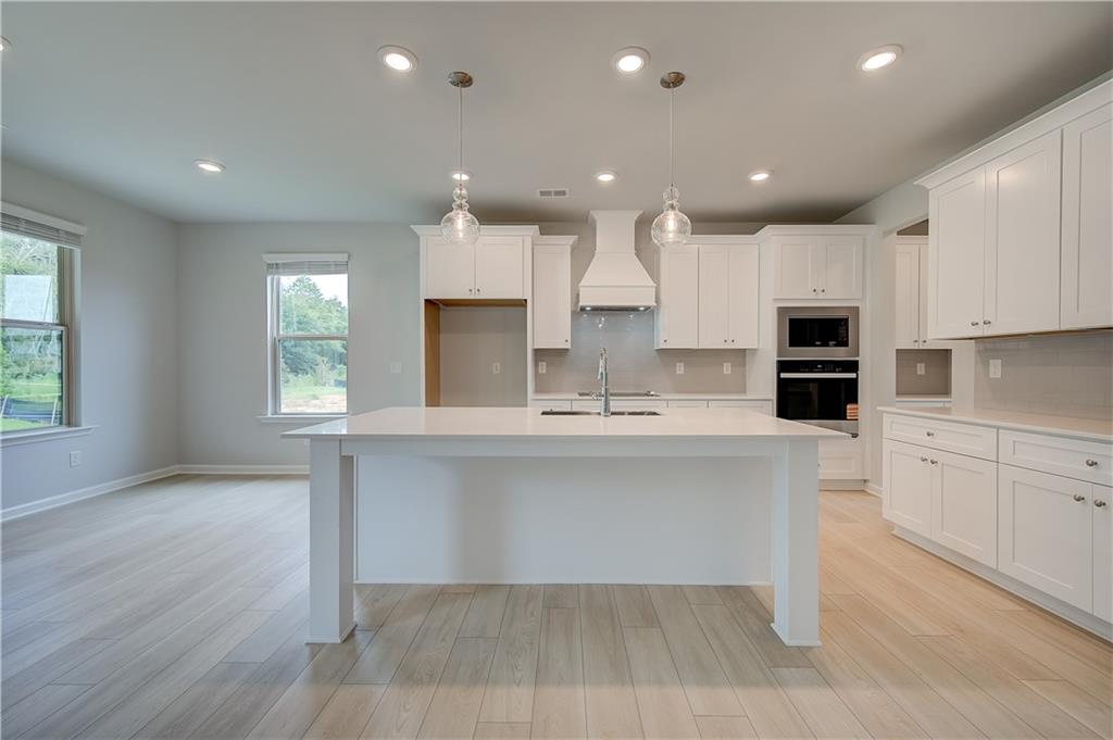 343 Linford Drive Locust Grove, GA 30248 - Photo 8 of 36 a large white kitchen with kitchen island a sink a center island stainless steel appliances and a window