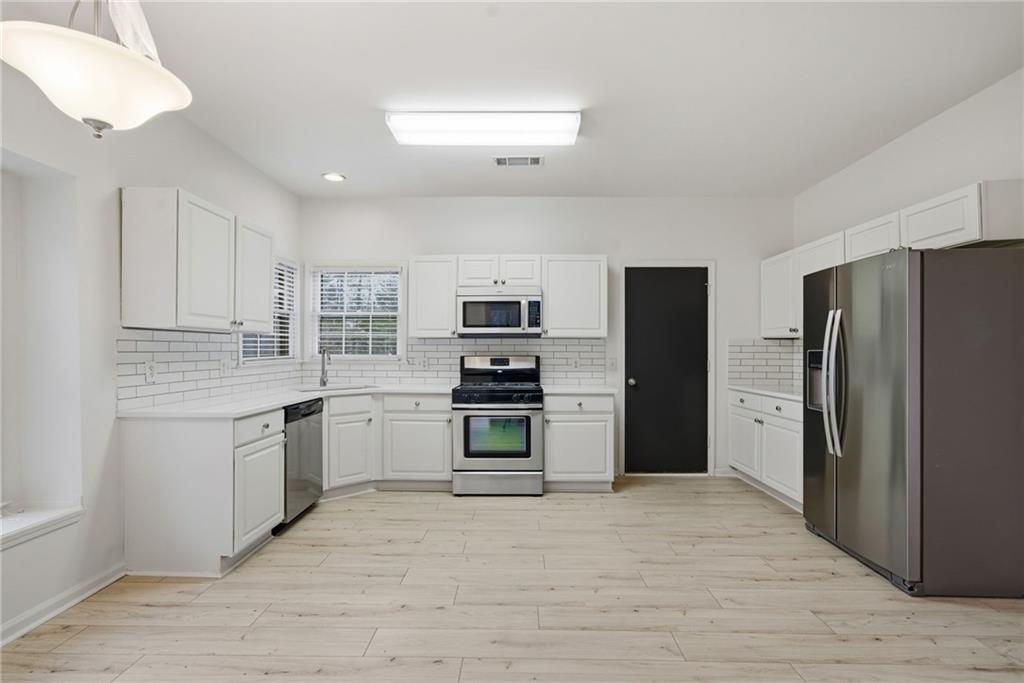 5868 Valine Way Sugar Hill, GA 30518 - Photo 12 of 32 a kitchen with granite countertop a refrigerator and a stove top oven