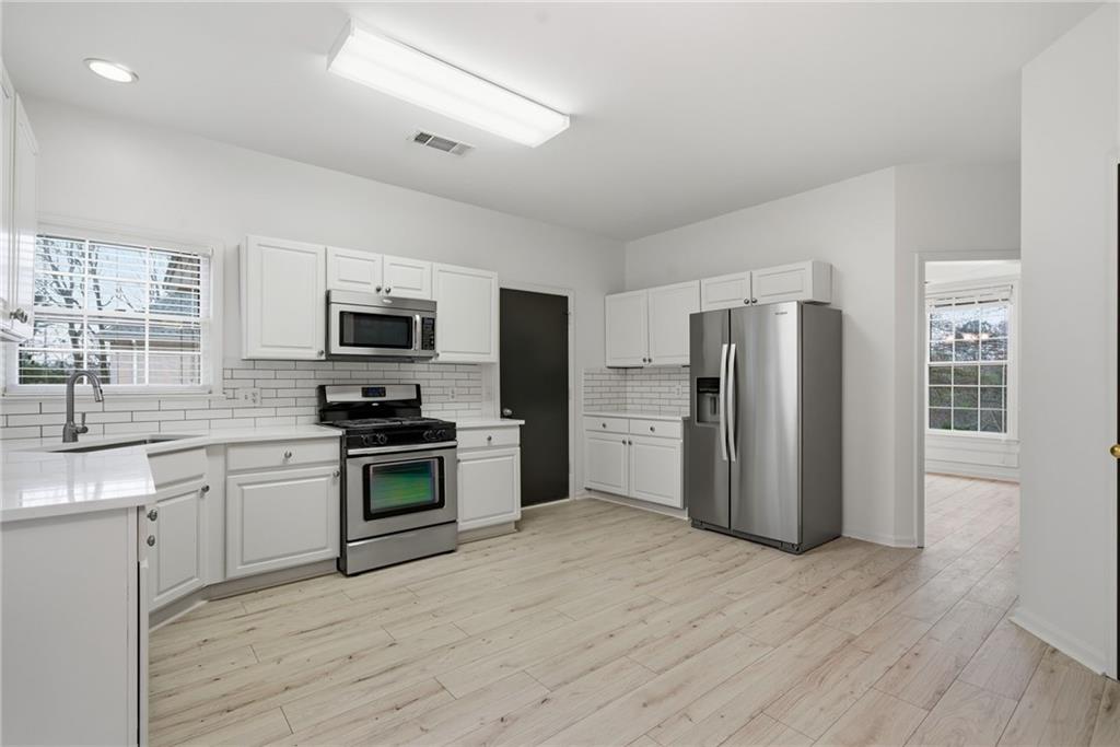 5868 Valine Way Sugar Hill, GA 30518 - Photo 15 of 32 a kitchen with stainless steel appliances a refrigerator stove microwave and sink