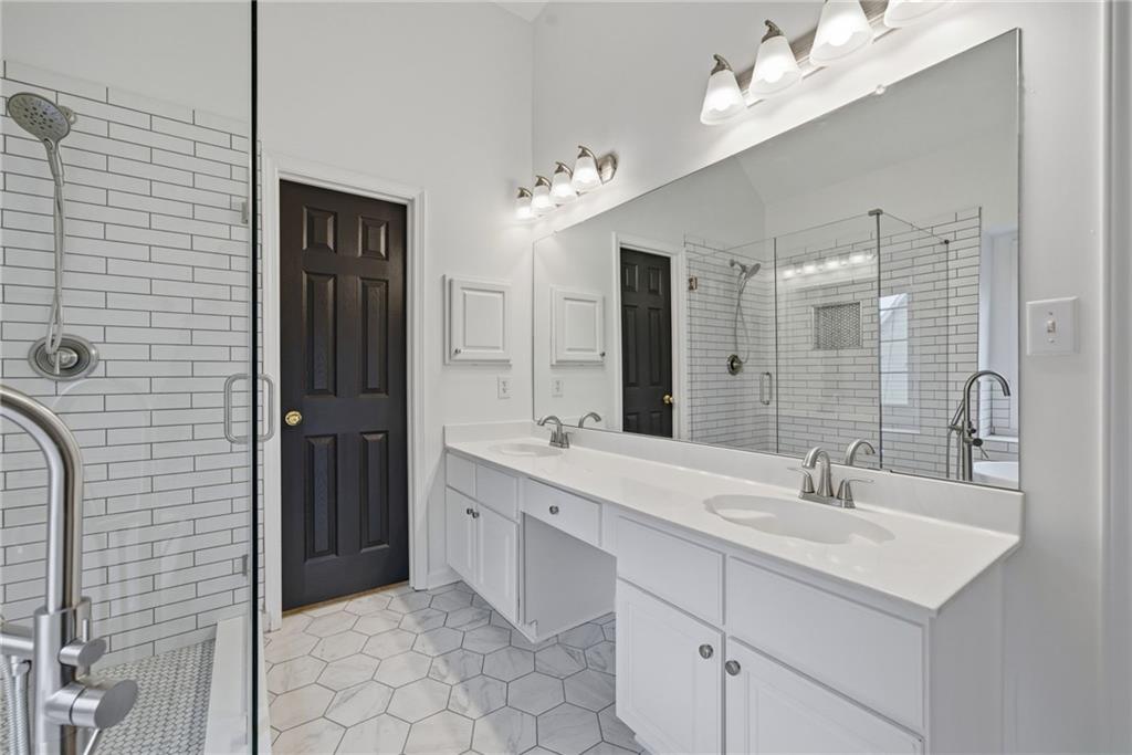 5868 Valine Way Sugar Hill, GA 30518 - Photo 20 of 32 a bathroom with a double vanity sink a mirror and a shower