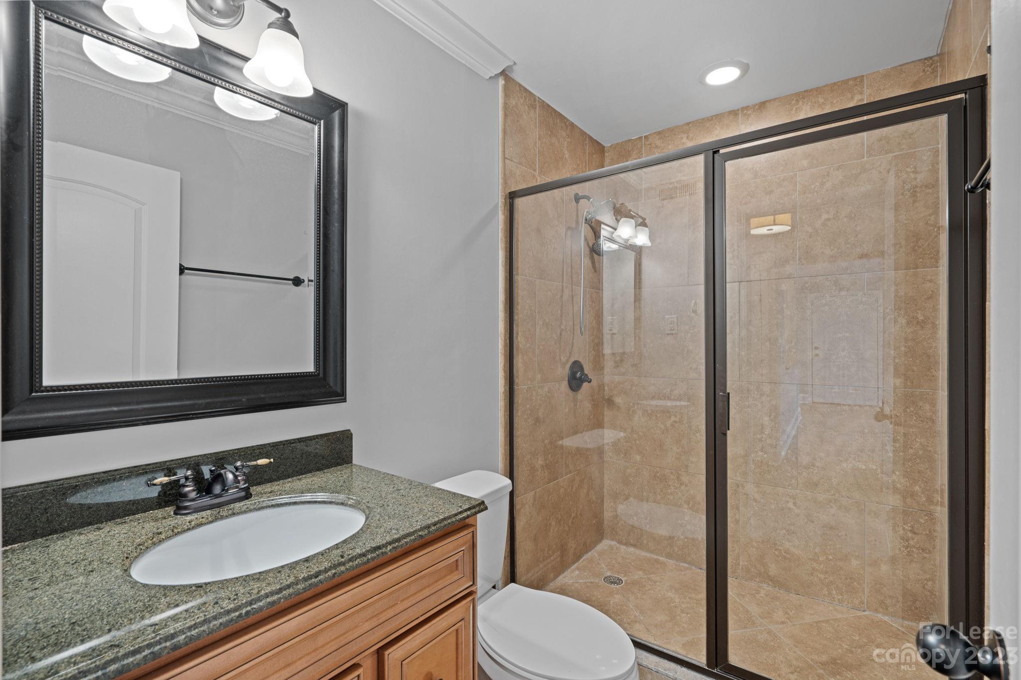 2614 Park Road Charlotte, NC 28209 - Photo 10 of 19 a bathroom with a granite countertop sink toilet a mirror a vanity and shower