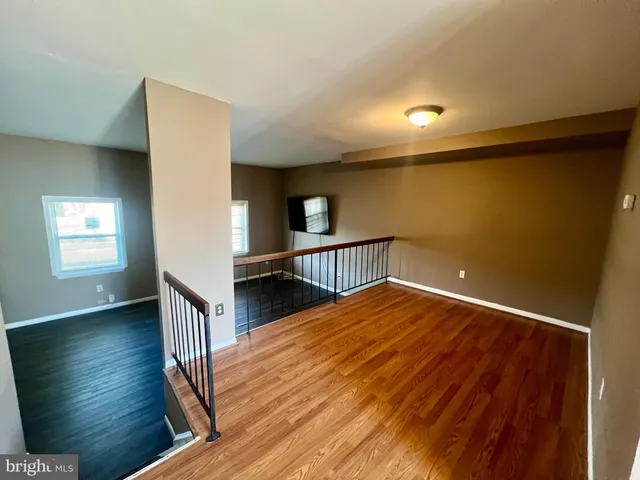 a view of a hallway with wooden floor and stairs