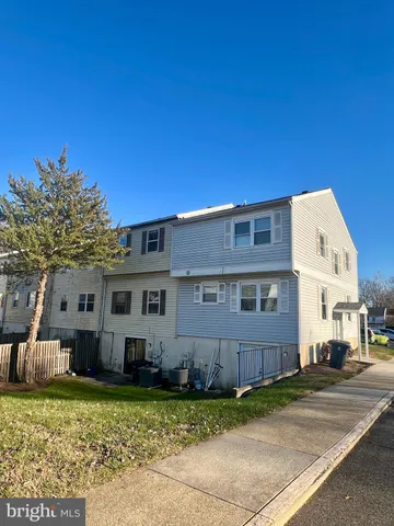 a front view of a building with garden and parking