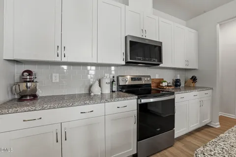 a kitchen with kitchen island wooden floors appliances and white cabinets