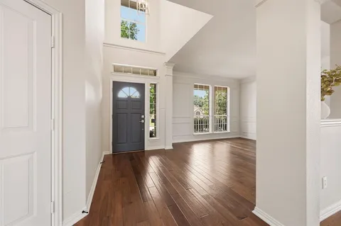 an empty room with wooden floor mirror and windows
