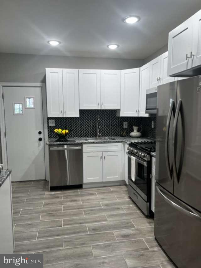 a kitchen with granite countertop a refrigerator a sink and white cabinets