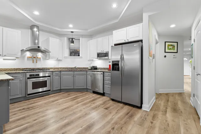 a kitchen with stainless steel appliances granite countertop a stove top oven a refrigerator and a sink