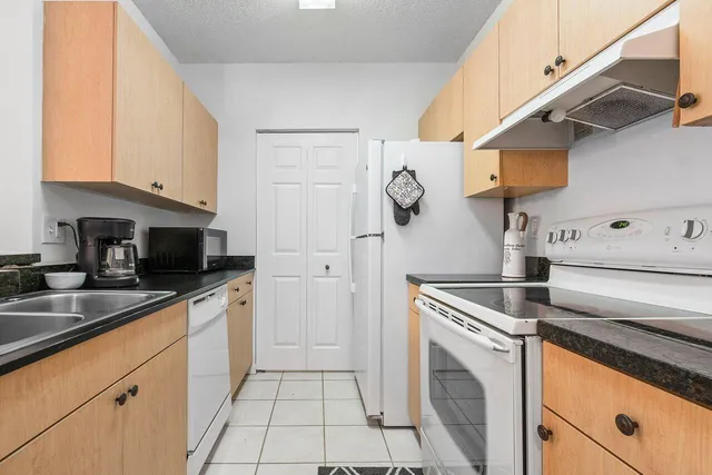 a kitchen with stainless steel appliances granite countertop a sink a stove and a refrigerator