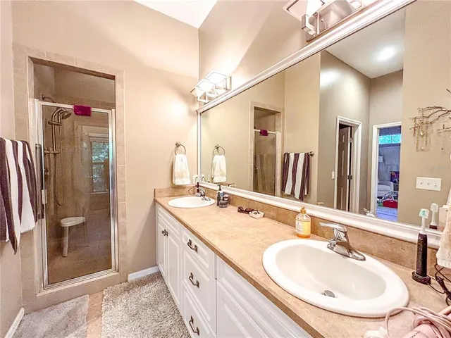 a bathroom with double vanity sinks and a shower
