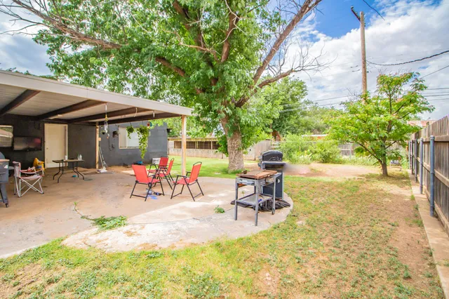 a view of a backyard with a table and chairs under an umbrella