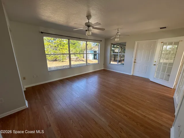 an empty room with wooden floor and windows