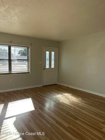 a view of an empty room with window and chandelier fan