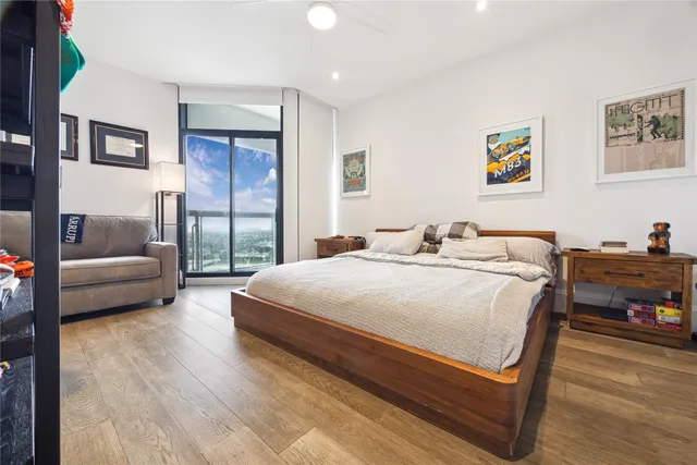 a spacious bedroom with a bed a couch and a potted plant on the dresser